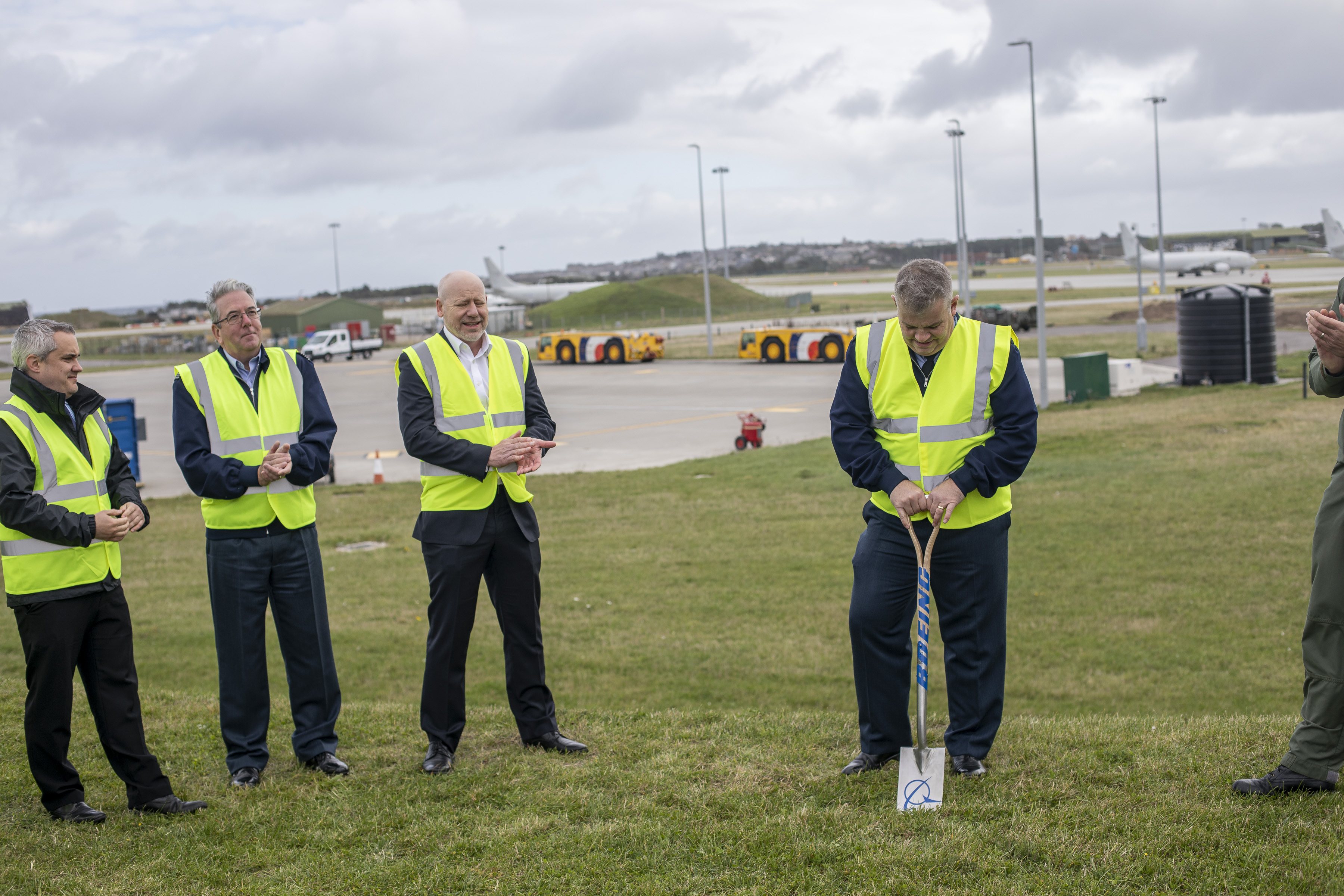 Image of personnel and civilians in high visibility jackets as one holds a shovel.